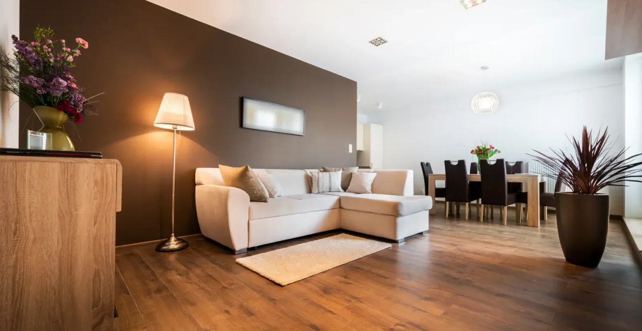 Un technicien mesure l'humidité d'un plancher de bois franc gondolé par un dégât d'eau dans un salon résidentiel.